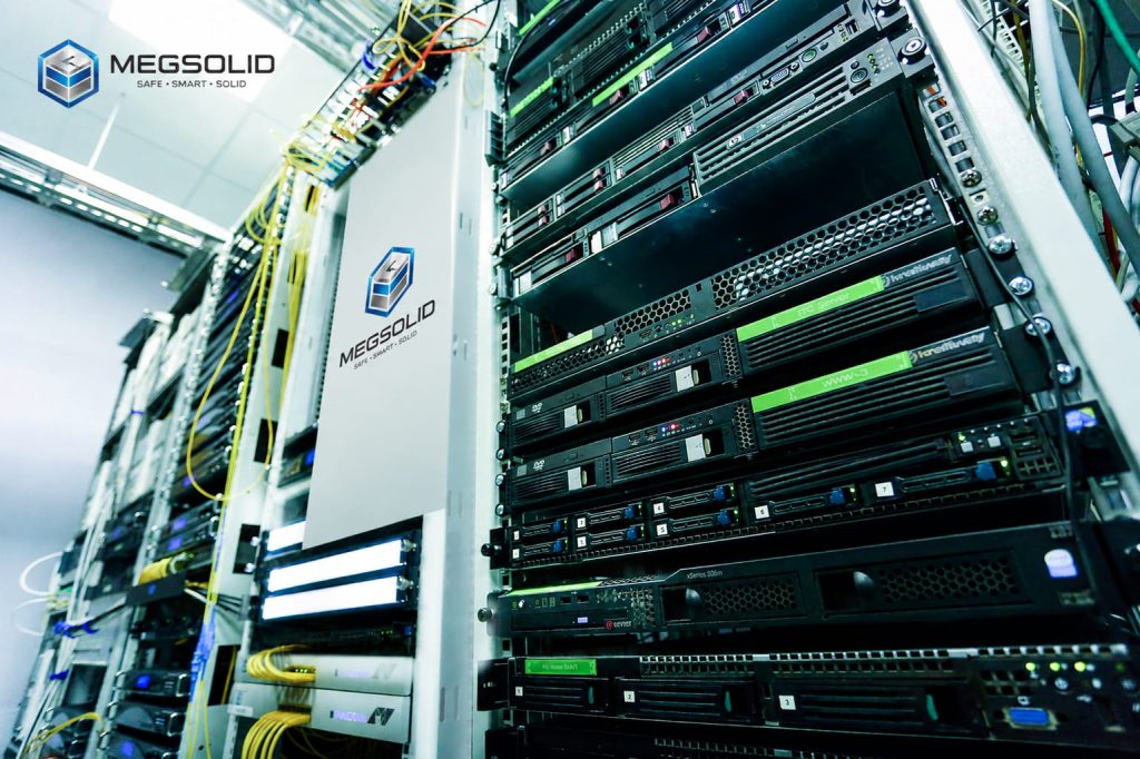 A close-up shot of a modern server room infrastructure featuring network cabling, blade servers, and a central white modular power unit branded with the MegSolid logo.