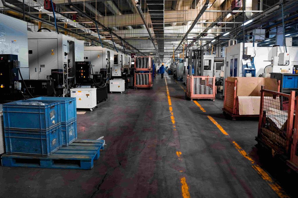 Wide interior shot of an industrial manufacturing and logistics floor in Johannesburg with yellow walkway lanes, automated machinery, and blue material crates, operating stably with MegSolid ESS backup power.